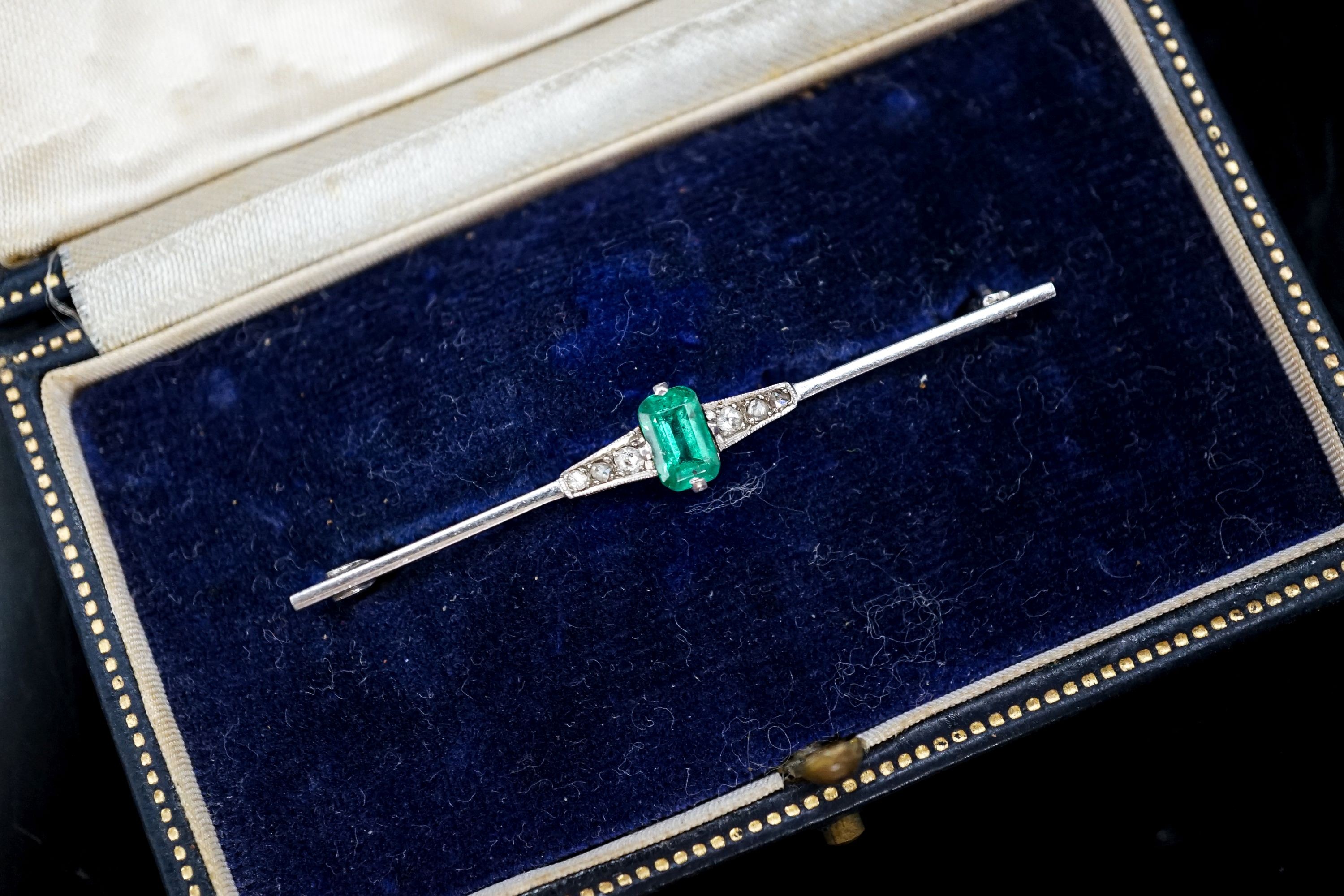 A boxed 1920's white metal (stamped pt), emerald and diamond chip set bar brooch, 51mm, gross weight 3.1 grams.